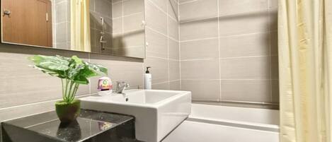 A bathroom with a sink, mirror, and shower.