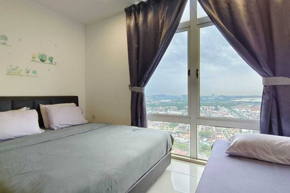 A bedroom with a bed, a window with curtains, and a city view.