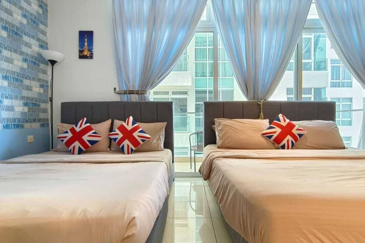 A hotel room with two beds, each with a headboard and pillows featuring the Union Jack flag.