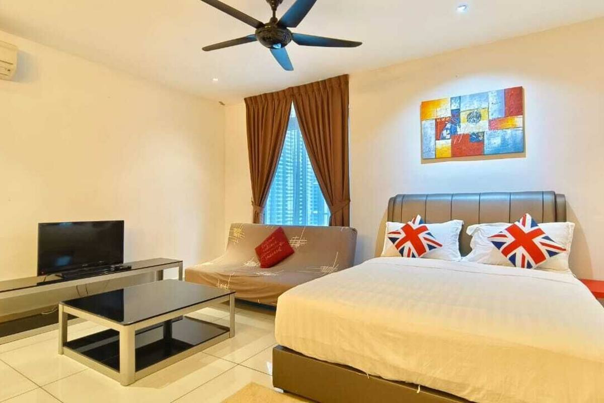 A modern hotel room with a bed, a TV, a sofa, and a ceiling fan.