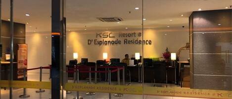 Η είσοδος στο D'Esplanade Residence του KSC Resort, με έναν πάγκο υποδοχής, προσωπικό και ένα γυάλινο διαχωριστικό.