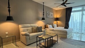 A modern hotel room with a sofa, a bed, a coffee table, and a ceiling fan. - JB City Shopping Mall Apartment (Johor Bahru)