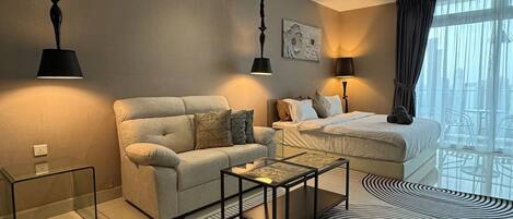 A modern hotel room with a sofa, a bed, a coffee table, and a ceiling fan.
