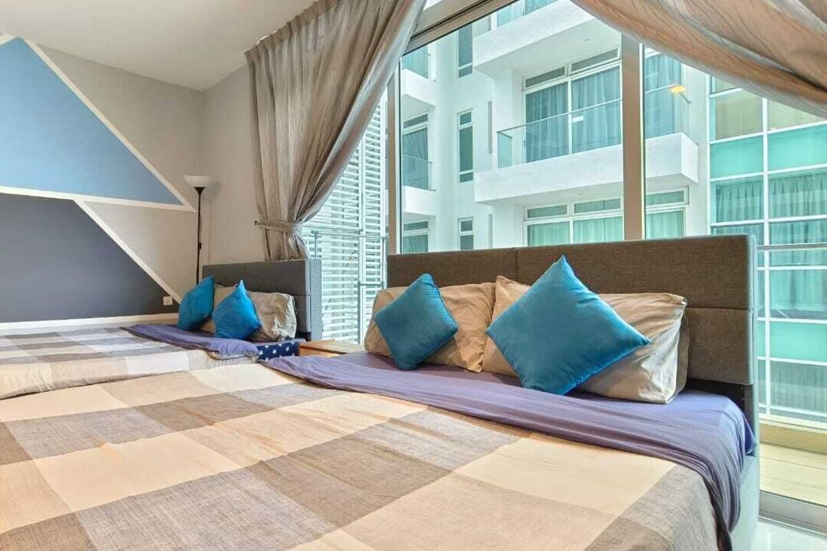 A hotel room with two beds, a large window, and a view of the building outside.