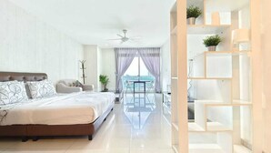 A modern bedroom with a large bed, a balcony with a view, and a white shelving unit. - JB City Shopping Mall Apartment (Johor Bahru)