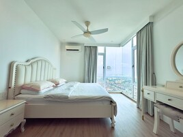 A bedroom with a bed, a vanity, a ceiling fan, and a large window with curtains.