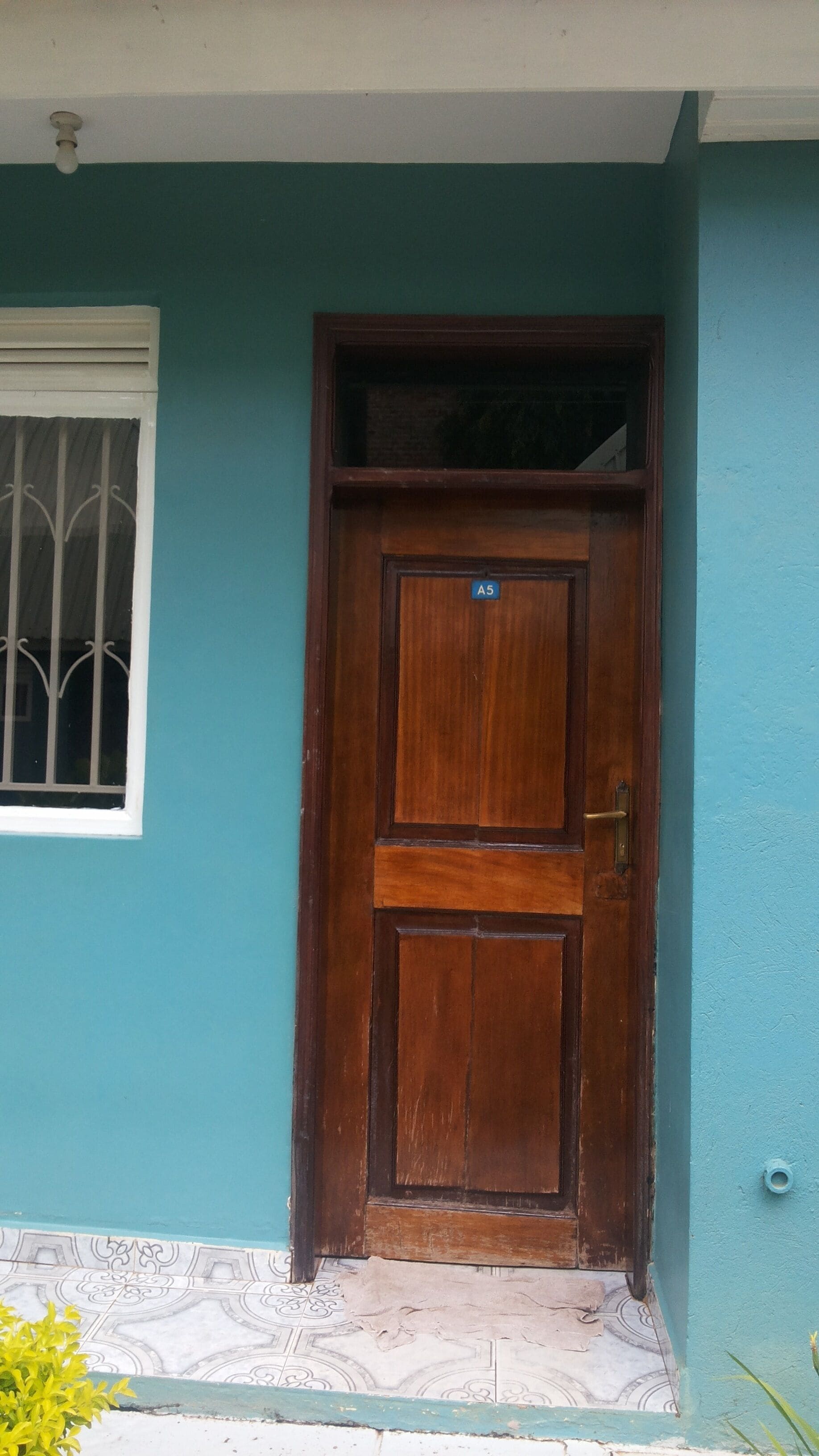 Una puerta de madera con un picaporte de metal y una pequeña etiqueta que dice "A5".