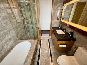 Une salle de bain moderne dotée d’une douche à parois de verre, d’une baignoire sur pieds, d’un meuble-lavabo avec miroir et de toilettes.