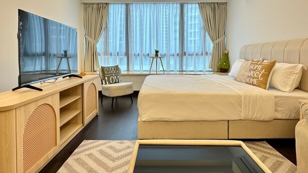 Une chambre d’hôtel moderne dotée d’un grand lit, d’une télévision, d’un bureau et d’une fenêtre avec des rideaux.