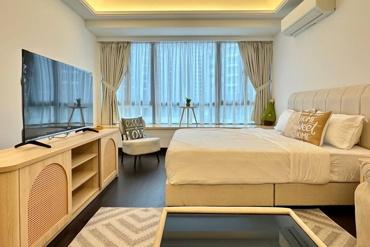 Ein modernes Hotelzimmer mit einem großen Bett, einem Fernseher, einem Schreibtisch und einem Fenster mit Vorhängen.