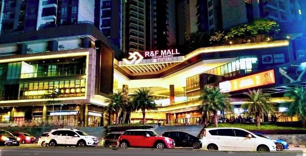 Un immeuble à plusieurs étages, reconnaissable à son grand panneau indiquant la présence d’un centre commercial R&F, qui se distingue par son architecture moderne, avec des façades en verre et un vaste espace d’entrée.