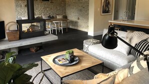 Ein gemütliches Wohnzimmer mit Steinwand, Kamin, Essbereich und einer Küche mit Spüle.