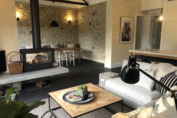 Open plan living, double sided fireplace opens out onto deck with paddock views