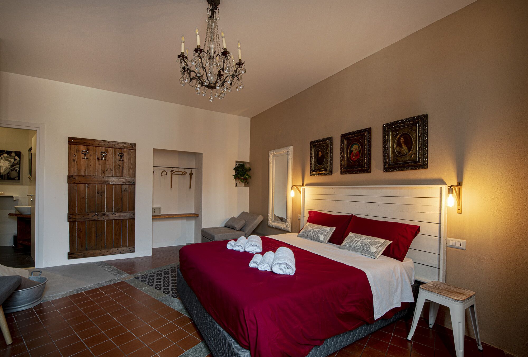 Un'ampia camera da letto con un letto grande, un lampadario e un'armadio in legno.