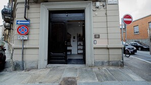 Entrada de un edificio con una puerta negra, un cartel de no estacionamiento y una señal de dirección.