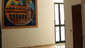 A spacious room with a large painting of a building on the wall, a door, and a window. - B&B San Francesco (Nicosia)
