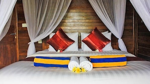 A bed with white linens, red pillows, and blue and yellow striped pillows. - Dream Beach Berlian (Lembongan Island)