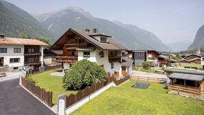 A mountain lodge with a wooden facade, a balcony, and a view of the surrounding mountains. - Spacious apartment for up to 9 people with garden (Umhausen)