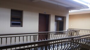 A corridor with a metal railing, a door labeled '42', and a window with blinds. - Highway Motel (Nebbi)