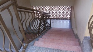 A staircase with a metal railing and a patterned wall at the top. - Highway Motel (Nebbi)