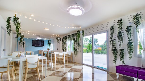 A modern interior with checkered flooring, white furniture, and hanging plants.