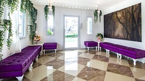 A hotel lobby with a checkered floor, purple seating, and a large painting on the wall.