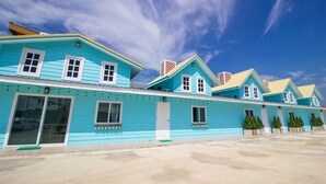 A row of turquoise buildings with white trim and multiple chimneys, likely a hotel or motel.
