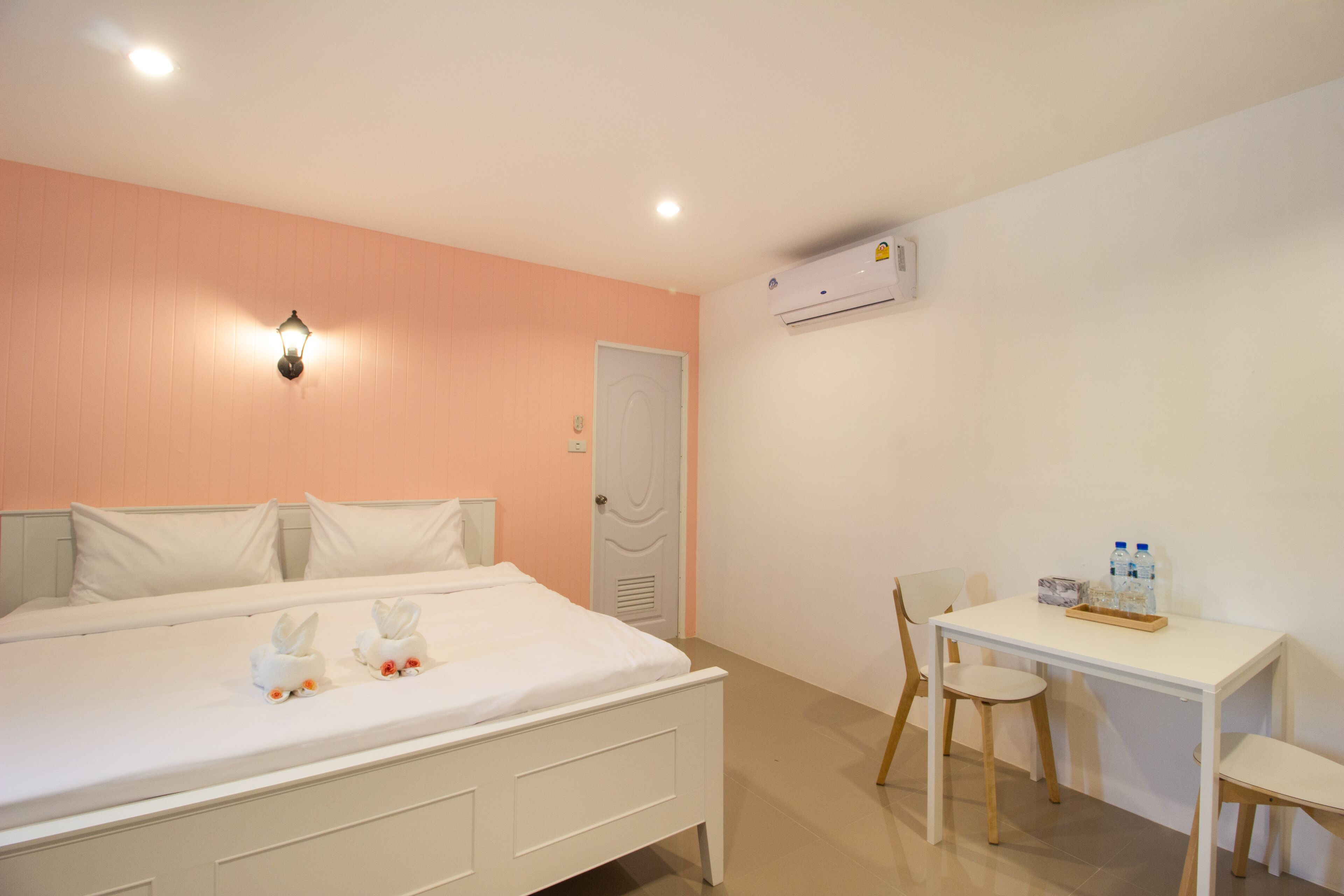 A hotel room with a bed, a desk, and an air conditioning unit.