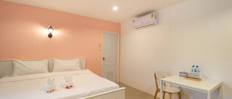 A hotel room with a bed, a desk, and an air conditioning unit.