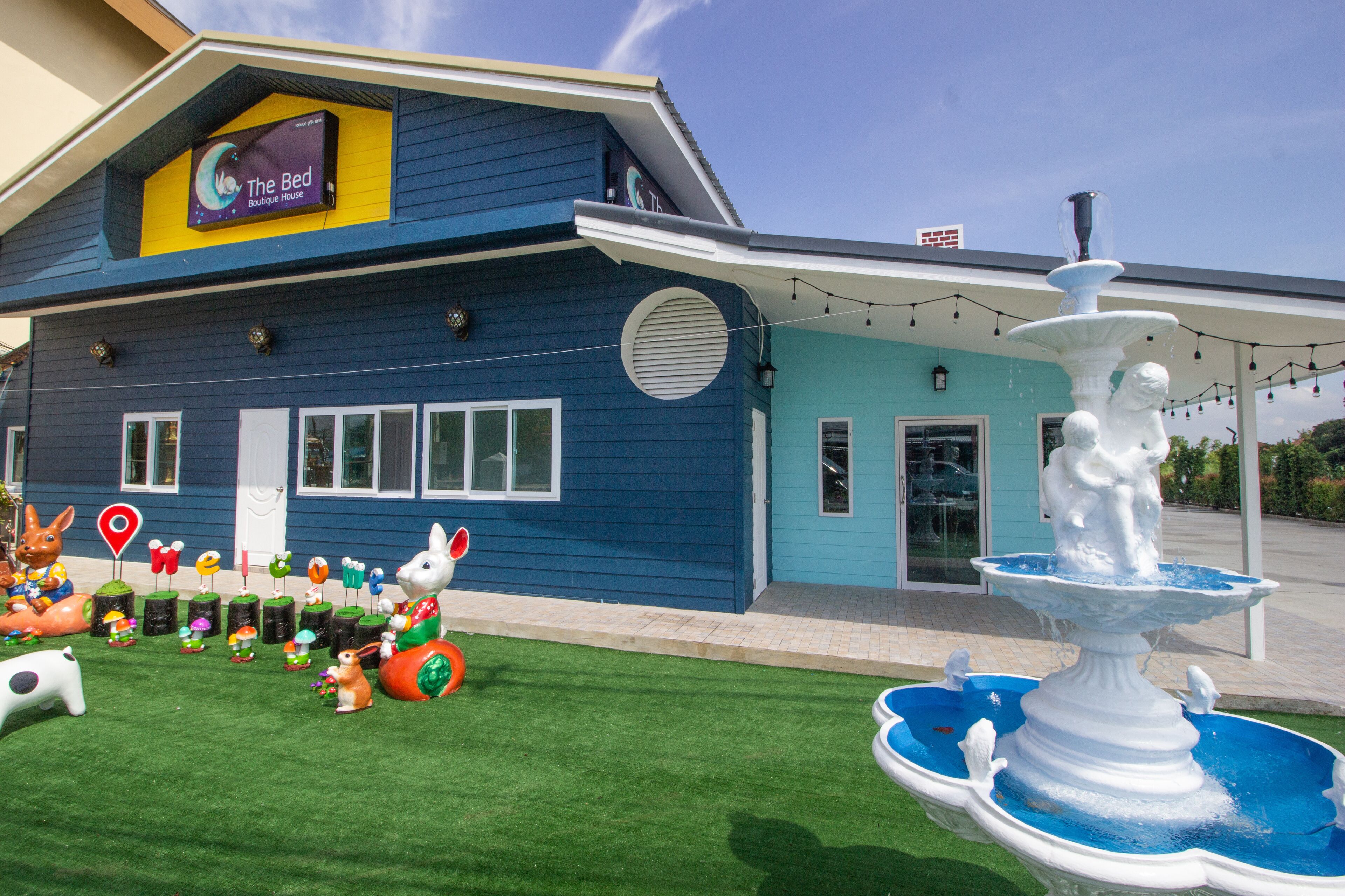 A boutique hotel with a blue exterior, a fountain, and various outdoor decorations including animal figures.