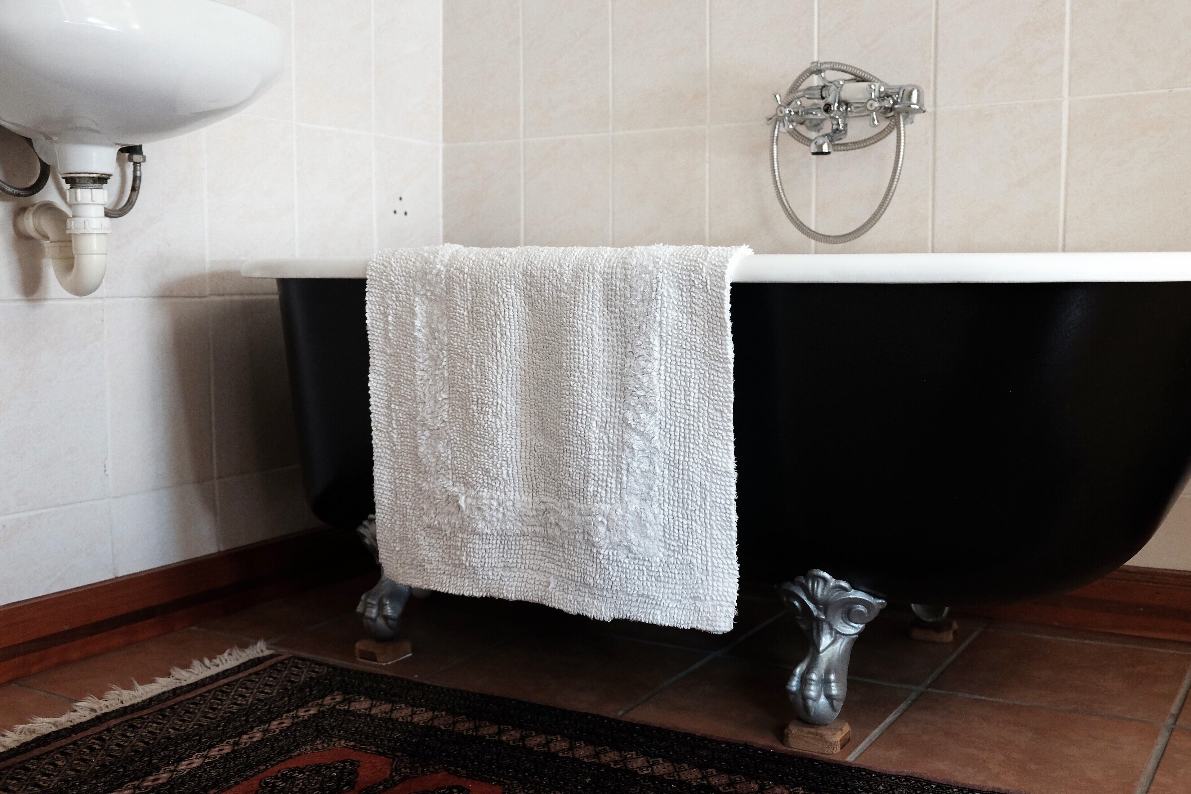Un baño con una bañera negra, un lavamanos blanco y un cabezal de ducha.
