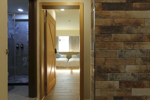 A hotel room with a wooden floor, a brick wall, and a bed with white bedding. - Color Balloons (Magong)