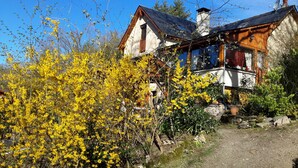 Une cabane rustique avec des fondations en pierre, un balcon en bois et une cheminée.