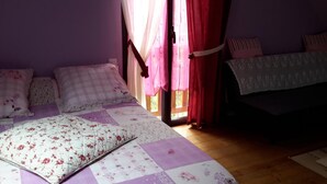 Une chambre à coucher avec un lit, des oreillers, une fenêtre avec des rideaux et une table de chevet.