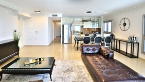 Ein modernes Wohnzimmer mit einer Ledersofa, einem Glastisch und einem Essbereich mit einer Chandelieber.