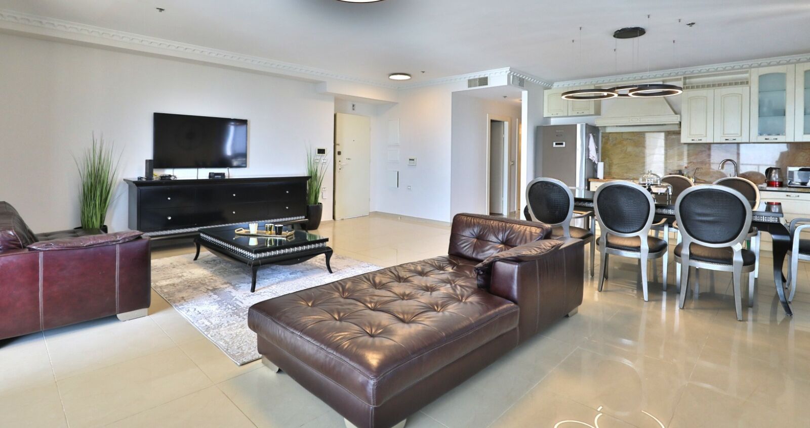 A modern living room with a leather sofa, a coffee table, and a flat-screen TV.