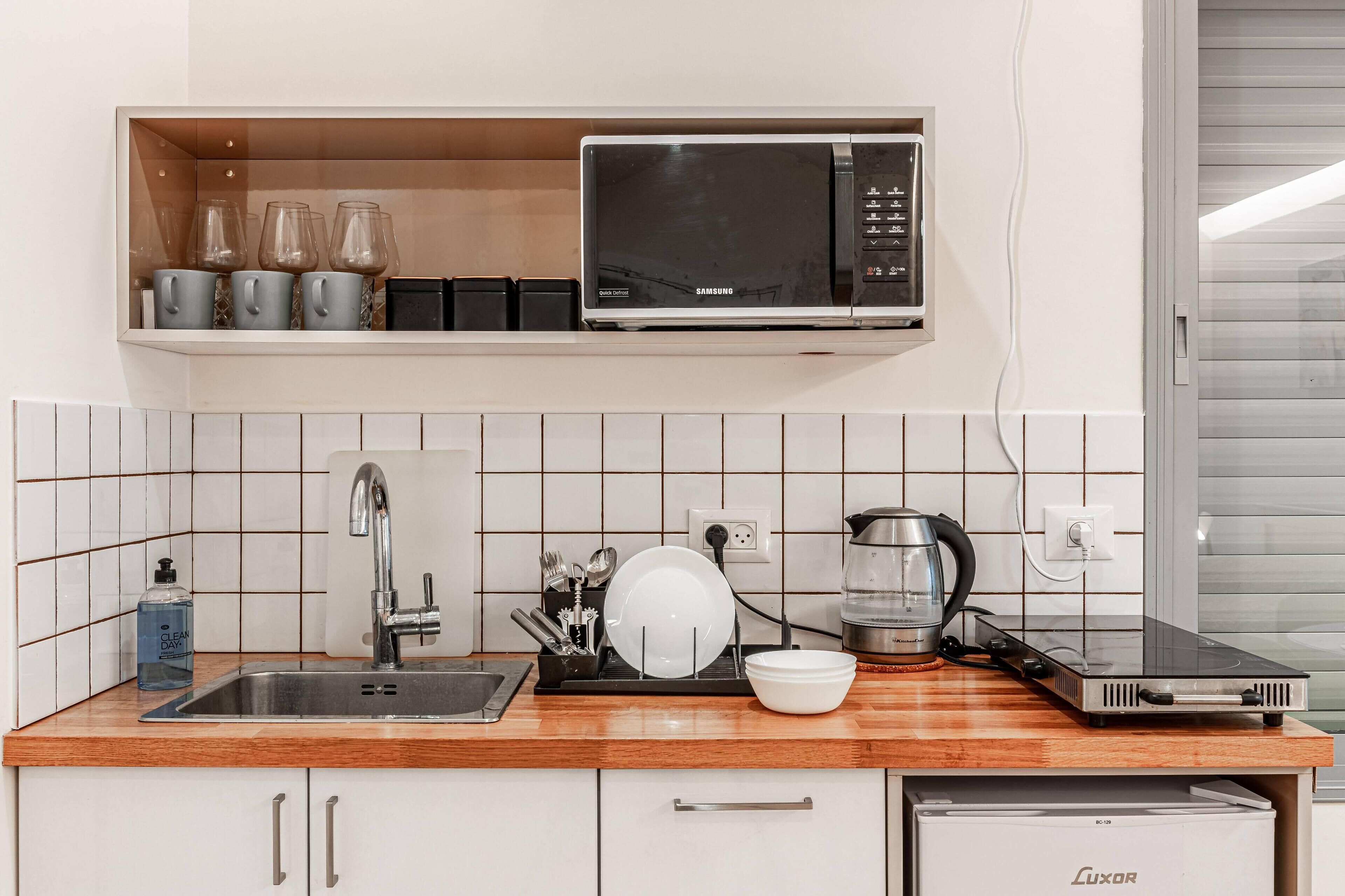 A kitchen with a microwave, sink, and a dish rack.