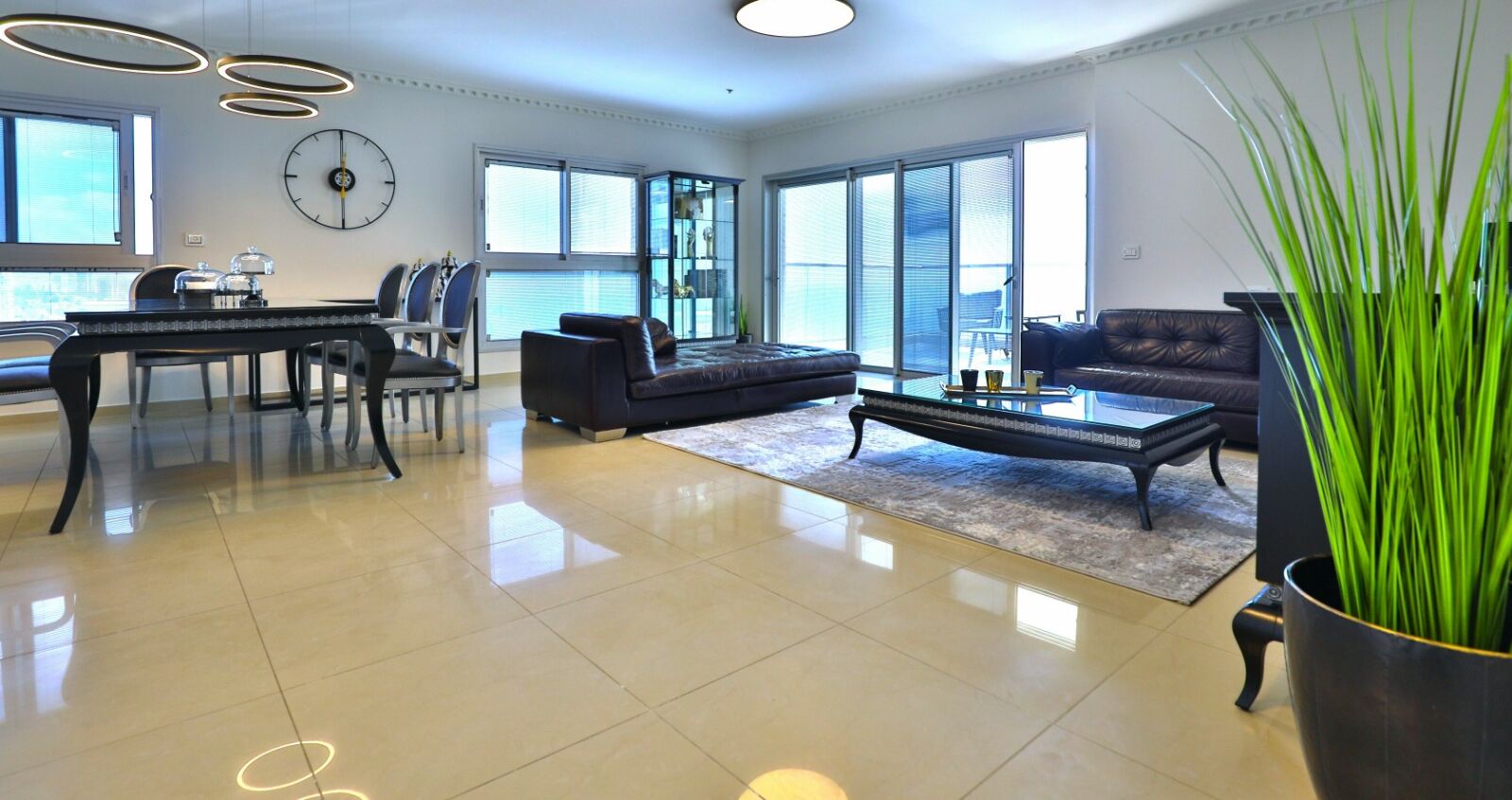 A spacious living room with a dining area, large windows, and a modern chandelier.