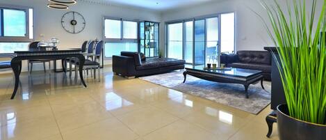 A spacious living room with a dining area, large windows, and a modern chandelier.