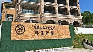 A multi-story building with a sign reading "RELAXURY" and Chinese characters. - Relaxury Beach House (Hengchun)