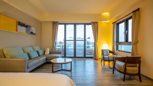 A hotel room with a sofa, a bed, a round coffee table, a chair, and a window with curtains. - Relaxury Beach House (Hengchun)