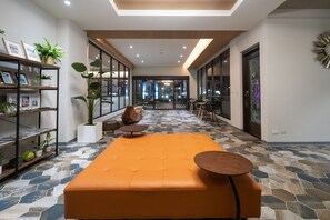 A modern interior with a central orange seating area, a wooden bookshelf, and a patterned floor. - Relaxury Beach House (Hengchun)