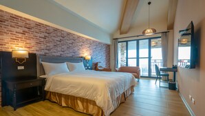 A hotel room with a brick wall, a bed with white bedding, a desk, and a chair. - Relaxury Beach House (Hengchun)