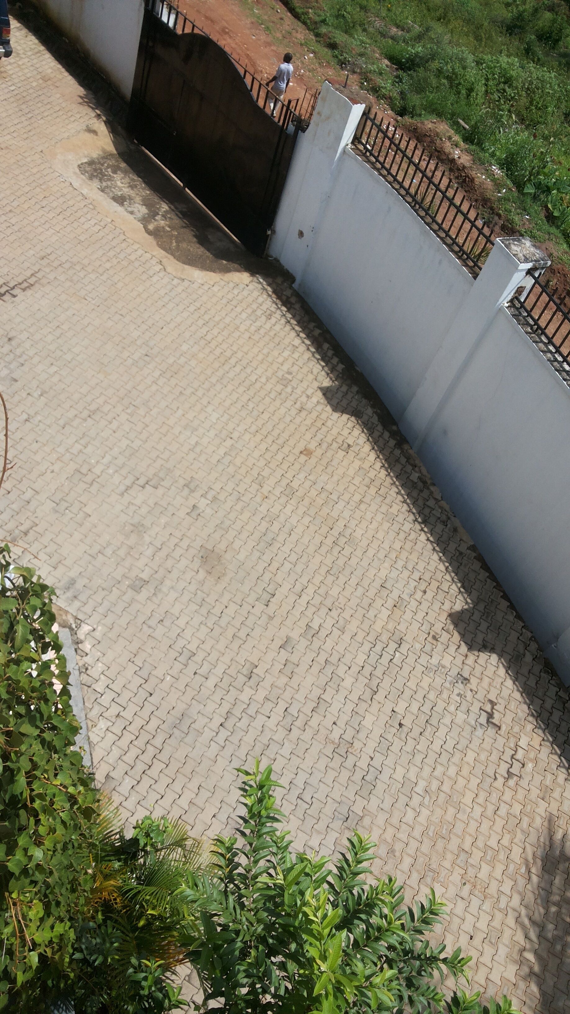 Un área pavimentada con una reja metálica y una pared blanca.