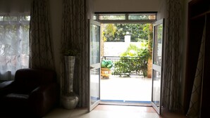 A room with a sliding glass door leading to a balcony with potted plants and a railing. - Rosevilla Hotel (Arua)