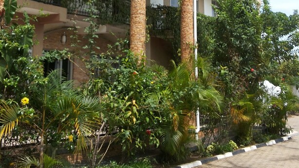 A building with multiple balconies, columns, and lush greenery. - Rosevilla Hotel (Arua)