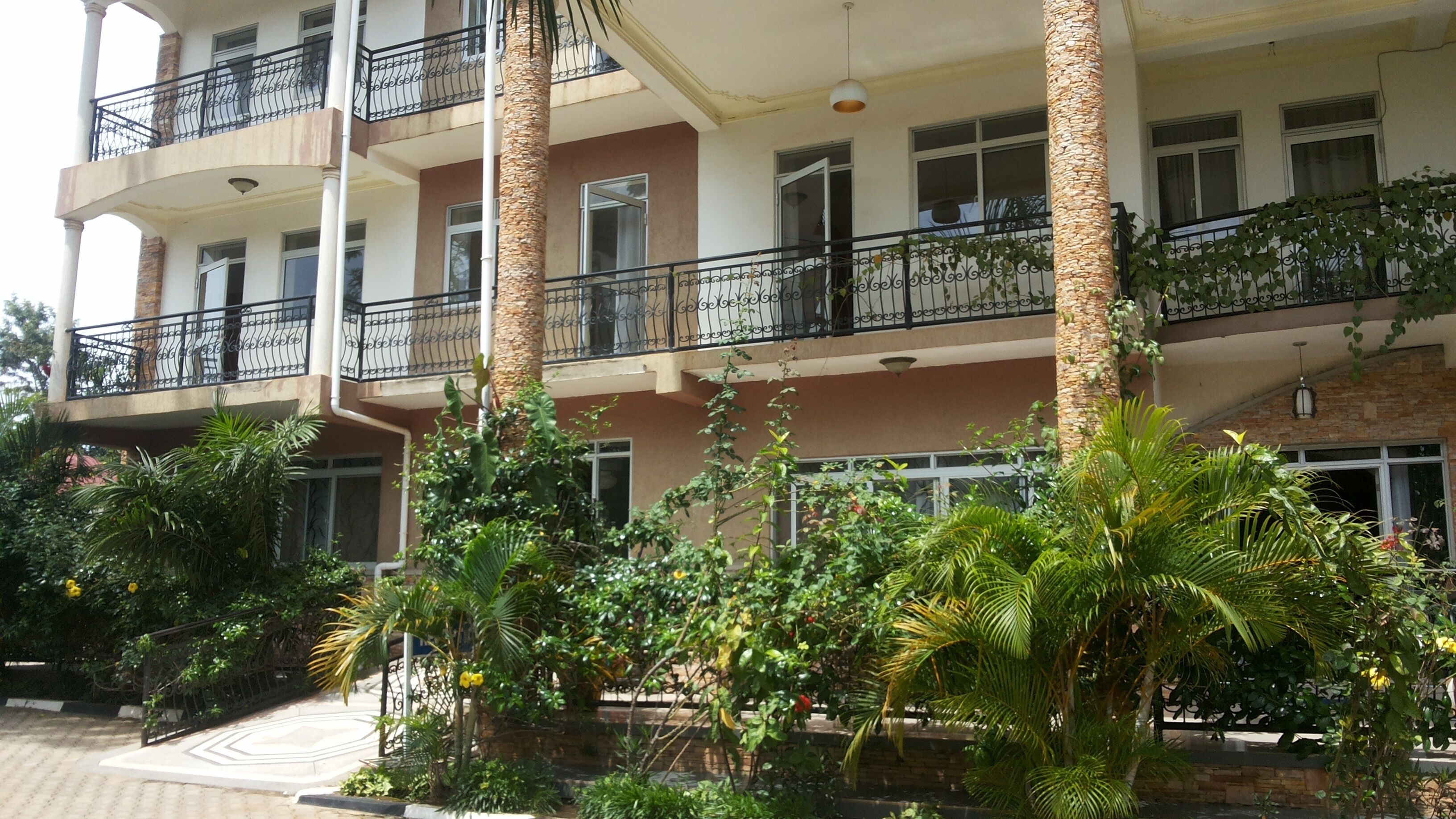 Un edificio de varios pisos con balcones, rodeado de abundante vegetación y palmeras.
