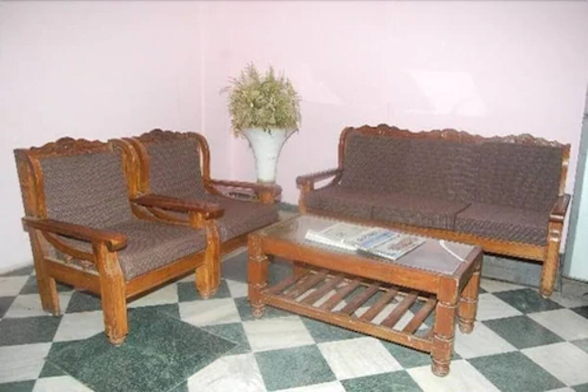 Una habitación con dos sillones de madera, un sofá, una mesita de centro y una planta en maceta.