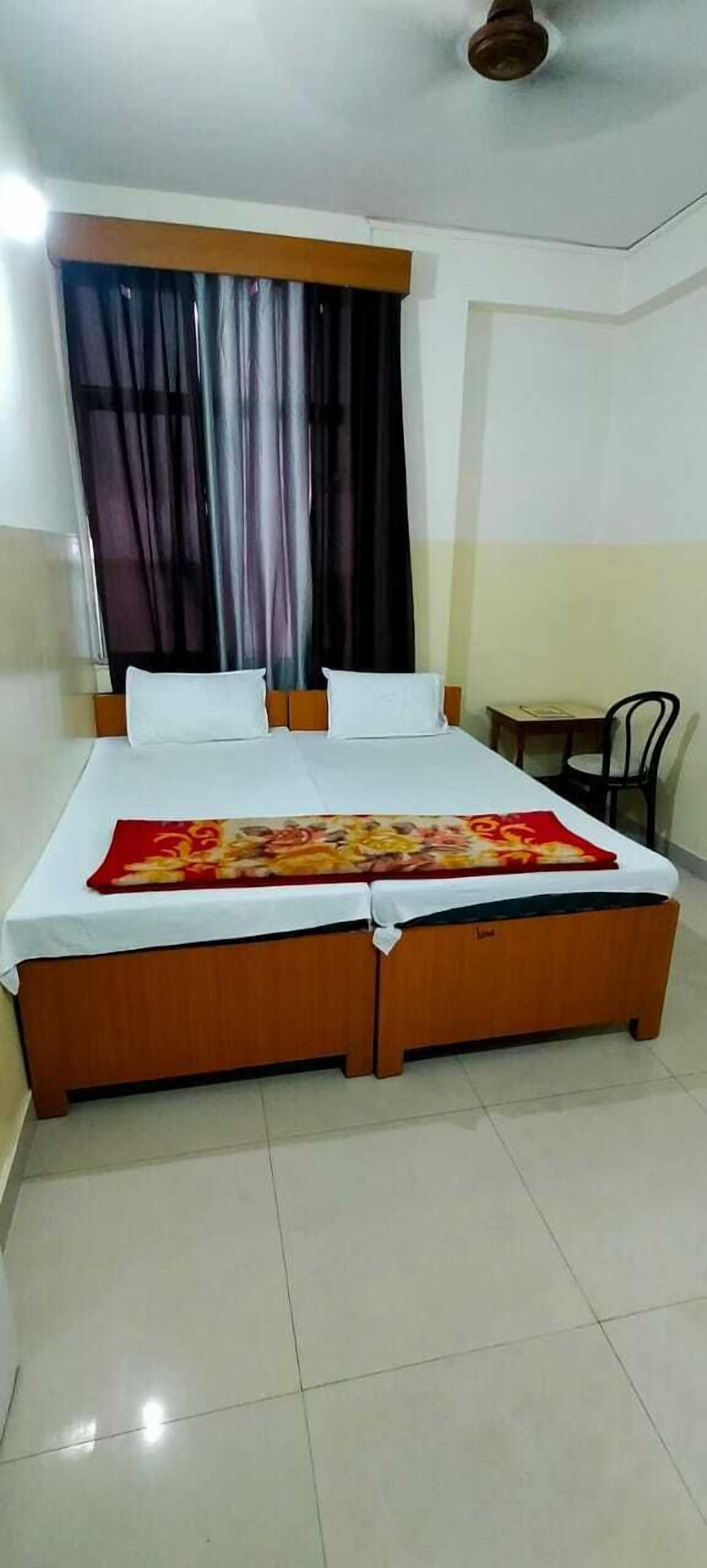 A hotel room with a bed, a nightstand, a chair, and a window with curtains.