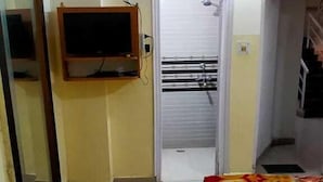 Ett hotellrum med en säng, en tv som är monterad på väggen, en dörr som leder till ett badrum och ett fönster.